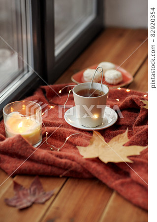 cup of tea and candle on window sill in autumn cup of tea and candle on window sill in autumn 82920354
