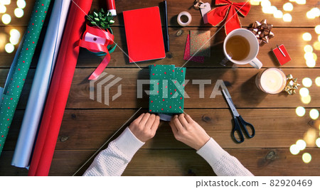 hands wrapping christmas gift on wooden table hands wrapping christmas gift on wooden table 82920469