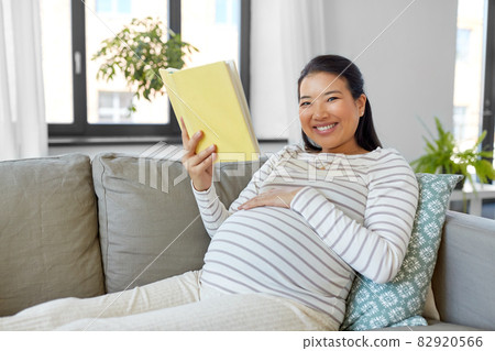 happy pregnant woman reading book at home 82920566