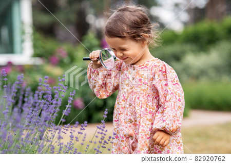 baby girl with magnifier looking at garden flowers baby girl with magnifier looking at garden flowers 82920762