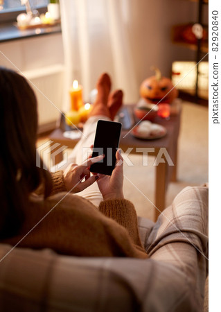 woman using smartphone at home on halloween 82920840