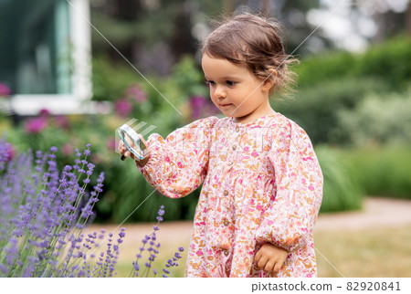 baby girl with magnifier looking at garden flowers baby girl with magnifier looking at garden flowers 82920841