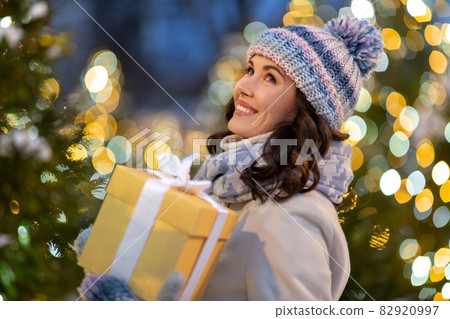 happy woman with christmas gift over lights happy woman with christmas gift over lights 82920997
