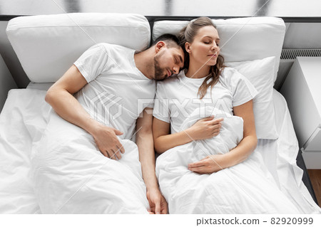 happy couple sleeping in bed at home 82920999
