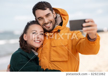 couple with smartphone on autumn beach 82921062
