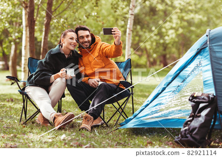 couple drinking tea and taking selfie at tent camp couple drinking tea and taking selfie at tent camp 82921114