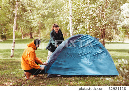 happy couple setting up tent outdoors happy couple setting up tent outdoors 82921118