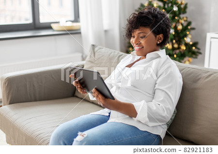 african woman with tablet pc at home on christmas african woman with tablet pc at home on christmas 82921183