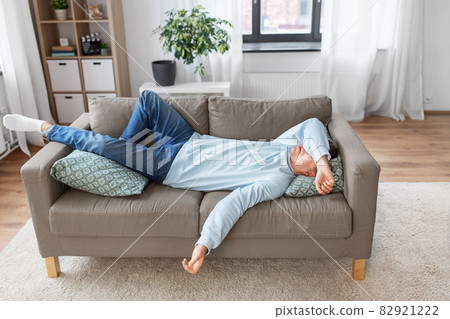 bored or lazy young man lying on sofa at home bored or lazy young man lying on sofa at home 82921222