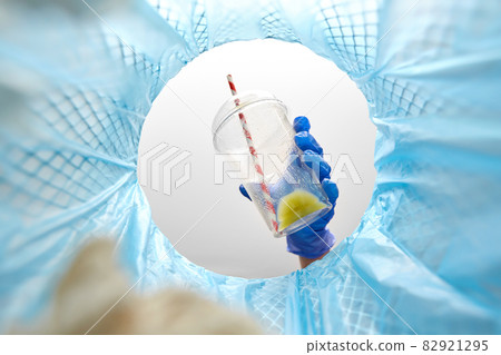 hand in glove throwing plastic cup into trash can hand in glove throwing plastic cup into trash can 82921295