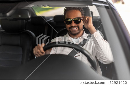 smiling indian man in sunglasses driving car smiling indian man in sunglasses driving car 82921420