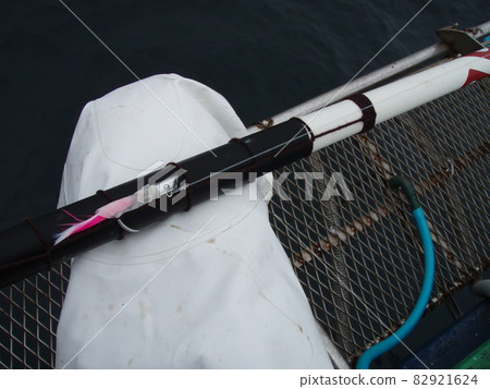 A traditional Japanese fishing method, skipjack tuna pole fishing, with the feet of a fisherman holding a kabura lure, waiting with his rod sticking out into the sea from the bow of his fishing boat. A traditional Japanese fishing method, skipjack tuna pole fishing, with the feet of a fisherman holding a kabura lure, waiting with his rod sticking out into the sea from the bow of his fishing boat. 82921624