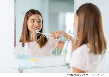 teen girl with electric toothbrush brushing teeth teen girl with electric toothbrush brushing teeth 82921735