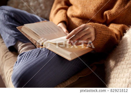woman in warm sweater reading book at home woman in warm sweater reading book at home 82921812