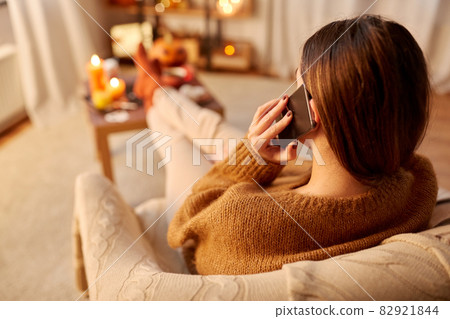woman calling on smartphone at home on halloween 82921844