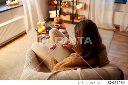woman writing to diary at home on halloween woman writing to diary at home on halloween 82921964