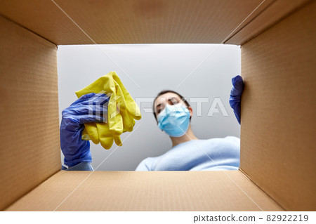woman in mask taking cleaning supplies from box 82922219