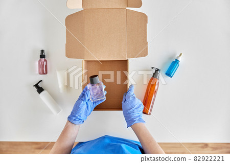 hands in gloves packing parcel box with cosmetics 82922221