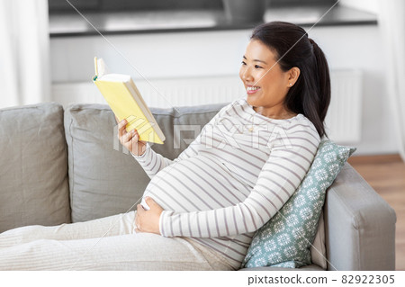 happy pregnant woman reading book at home happy pregnant woman reading book at home 82922305