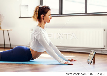 woman with tablet pc having online yoga class woman with tablet pc having online yoga class 82922362
