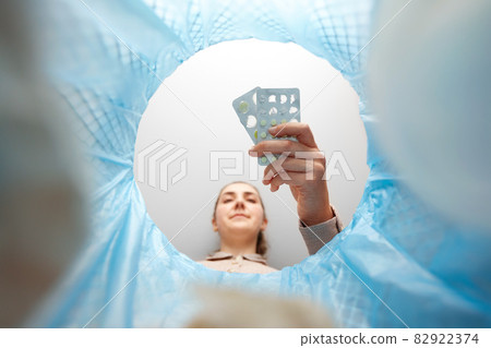 woman throwing old medicine pills into trash can woman throwing old medicine pills into trash can 82922374