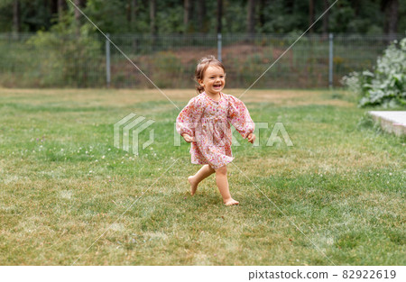 happy little baby girl running barefoot on grass 82922619