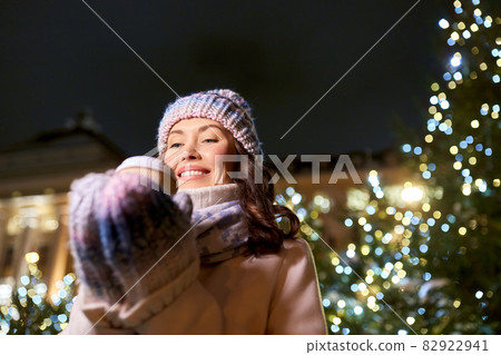happy woman drinking coffee over christmas lights 82922941