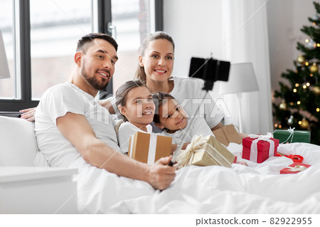 family with christmas gifts taking selfie in bed 82922955