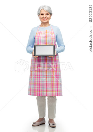 smiling senior woman in apron with tablet computer smiling senior woman in apron with tablet computer 82923122