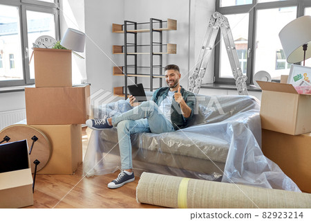 man with tablet pc and boxes moving into new home 82923214