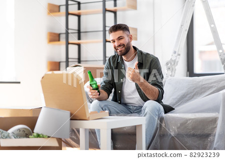 man with box of pizza and beer bottle at new home 82923239