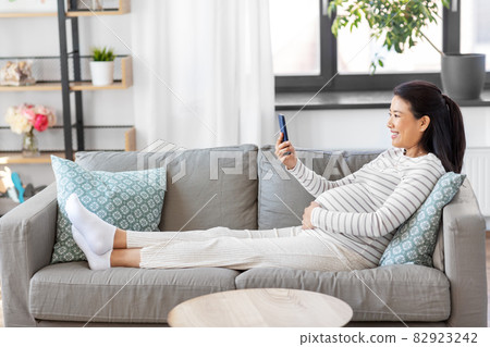 happy pregnant woman with smartphone at home 82923242