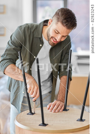happy man assembling coffee table at new home happy man assembling coffee table at new home 82923243