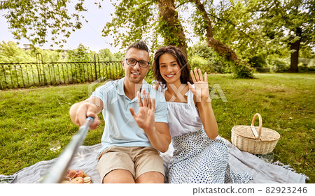 happy couple taking selfie at picnic in park 82923246