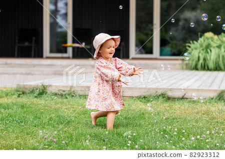 happy baby girl playing with soap bubbles outdoors happy baby girl playing with soap bubbles outdoors 82923312