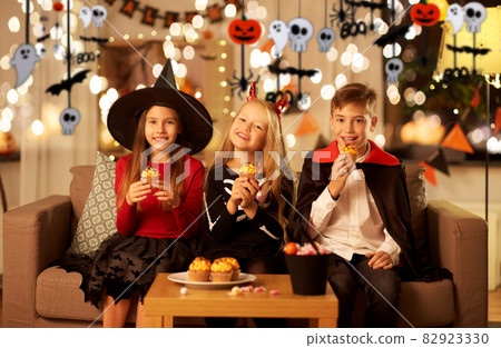 kids in halloween costumes eating cupcakes at home 82923330