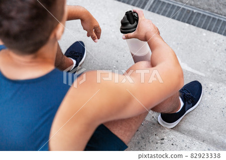 sportsman with shake in bottle sitting on stairs 82923338