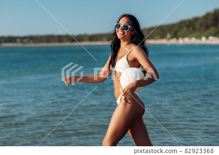 woman in bikini posing with volleyball on beach - Stock Photo