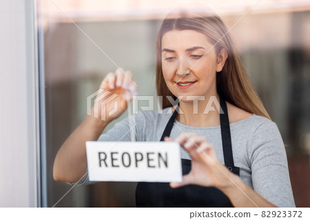 happy woman hanging reopen banner to door glass happy woman hanging reopen banner to door glass 82923372