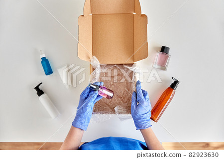 hands in gloves packing parcel box with cosmetics 82923630