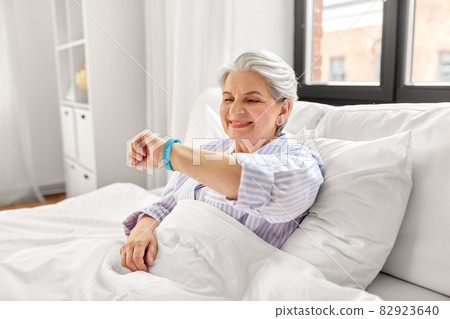happy old woman with health tracker sitting in bed 82923640