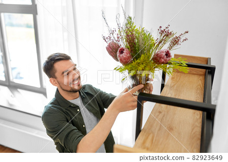 man decorating home with flowers in vase man decorating home with flowers in vase 82923649