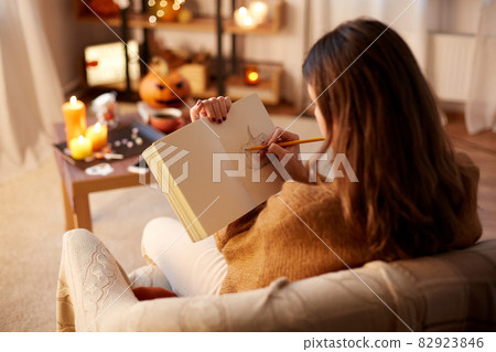 woman drawing in sketchbook at home on halloween woman drawing in sketchbook at home on halloween 82923846