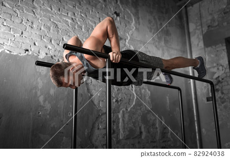 man doing push-ups on parallel bars in gym man doing push-ups on parallel bars in gym 82924038