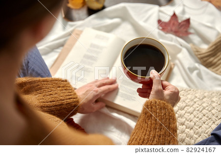 woman drinking coffee and reading book in autumn woman drinking coffee and reading book in autumn 82924167