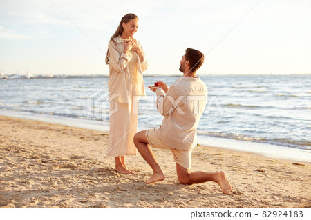 man with ring making proposal to woman on beach 82924183