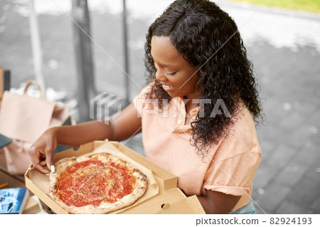 african student girl eating takeaway pizza in city african student girl eating takeaway pizza in city 82924193