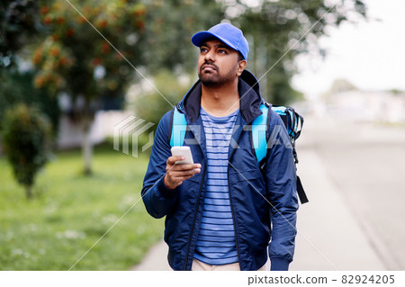 indian delivery man with bag and phone 82924205