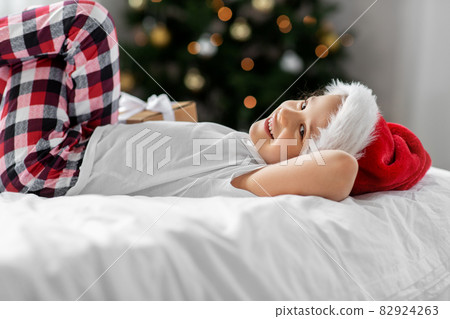 happy girl with christmas gift on bed at home 82924263