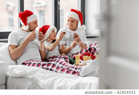 happy family eating coookies in bed on christmas 82924331